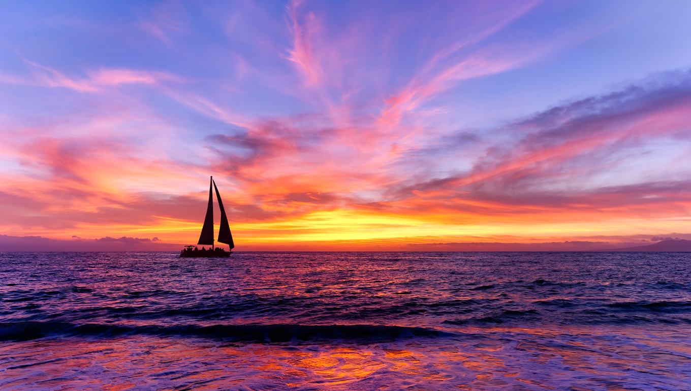 A sailboat on the water with a sunset in the background