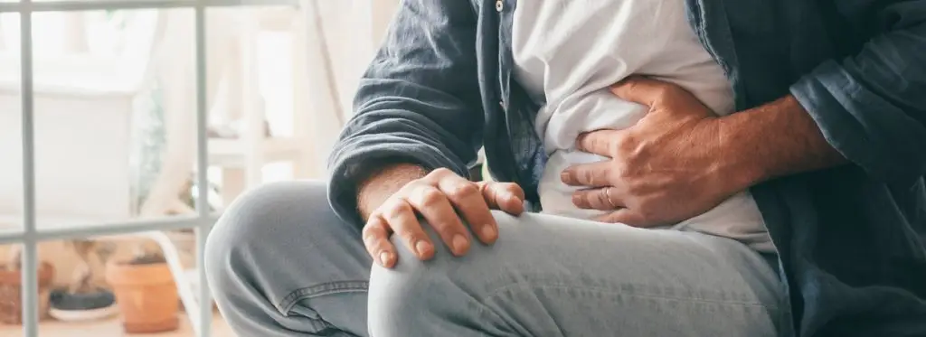 Man suffering with severe stomach pain sitting at home
